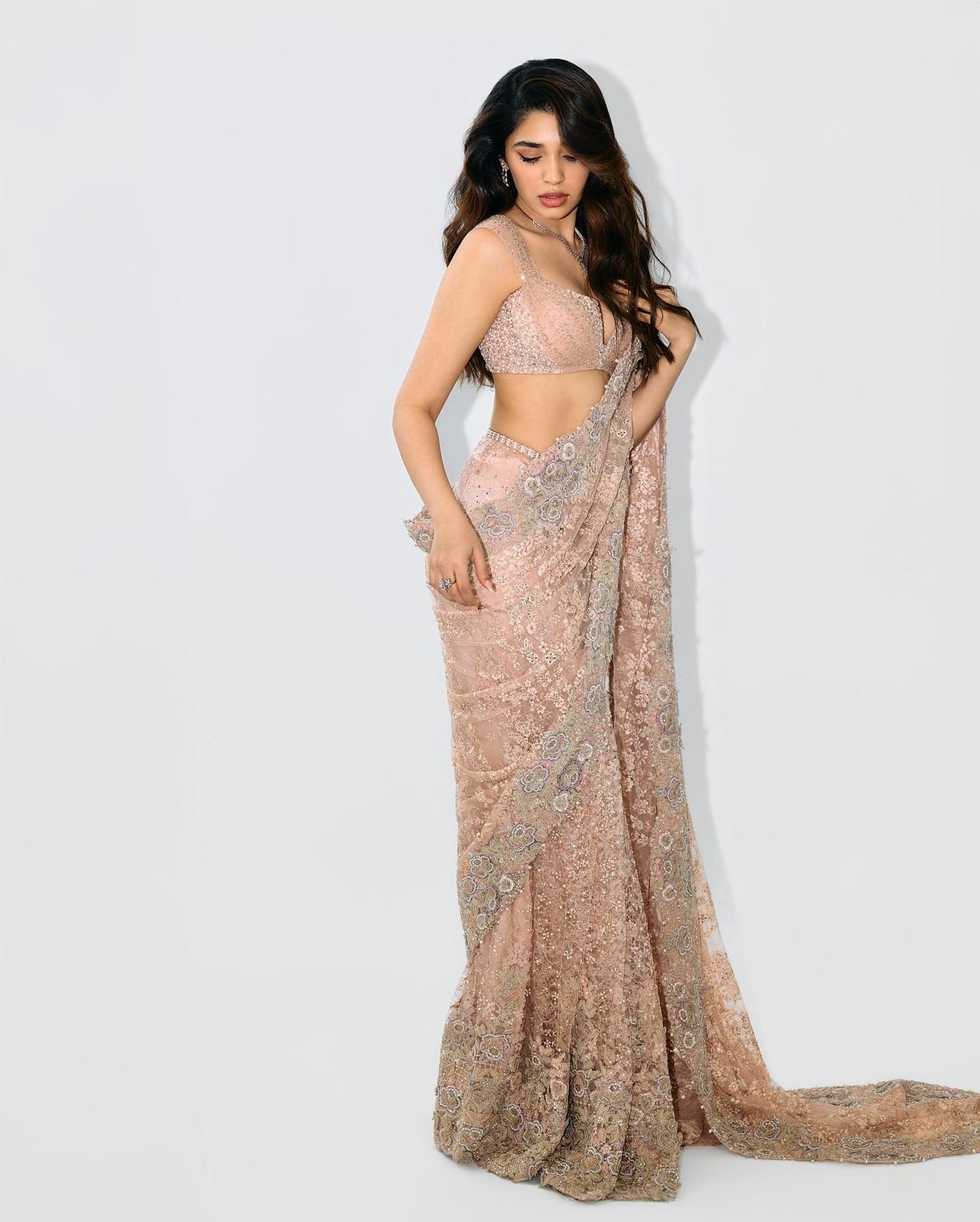 Krithi Shetty looks ethereal in this blush pink embellished saree featuring intricate floral embroidery and shimmering detailing. The matching sequin blouse with a plunging neckline adds glamorous touch.